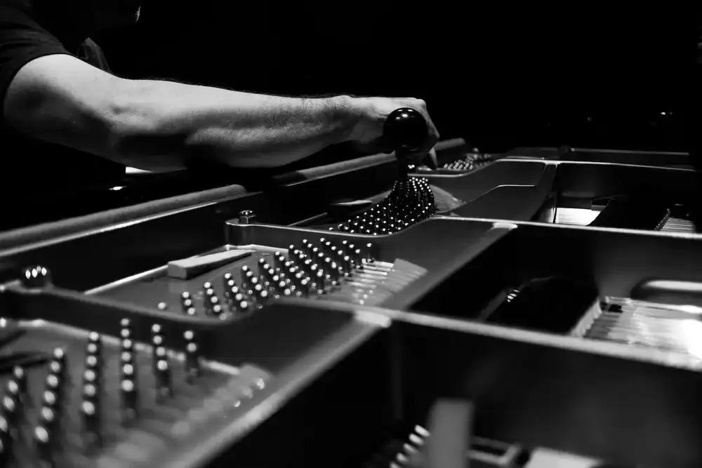 Piano technician reviewing a schedule on a clipboard beside an opened grand piano