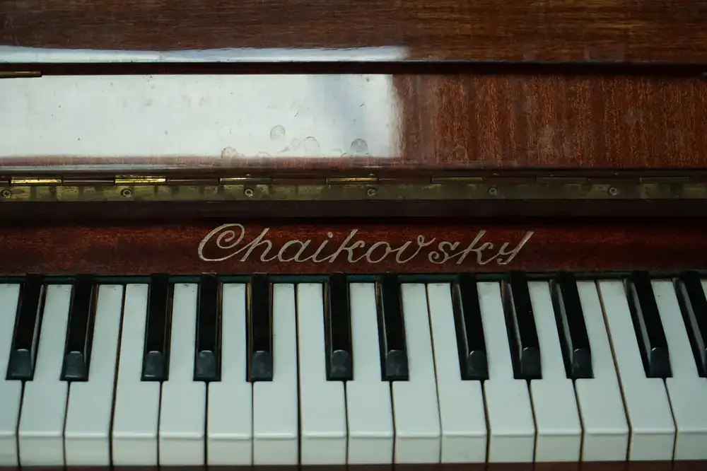 Craftsman carefully polishing the wooden case of a classic piano